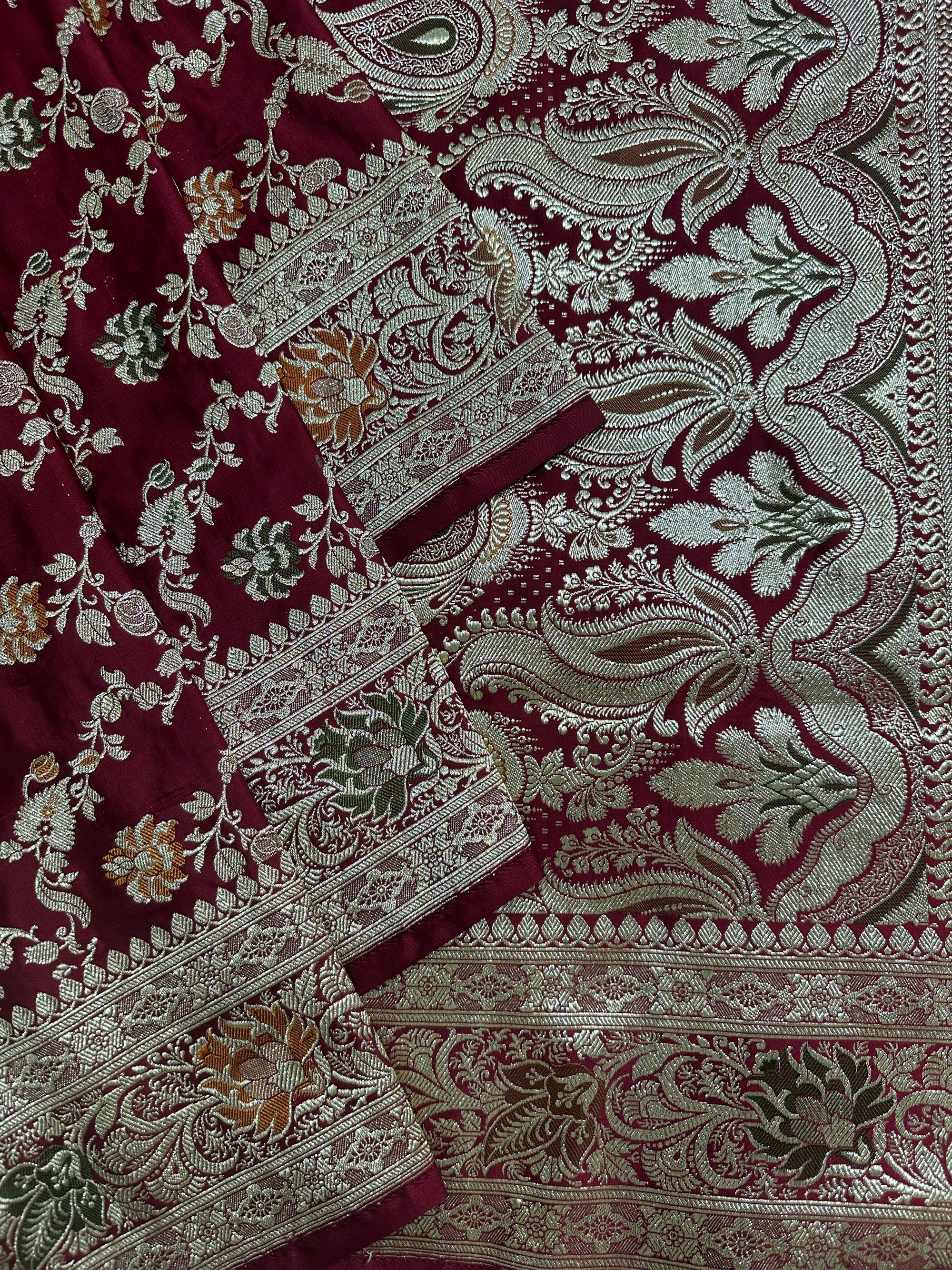 Close-up of Meenakari and floral zari work on maroon bridal saree